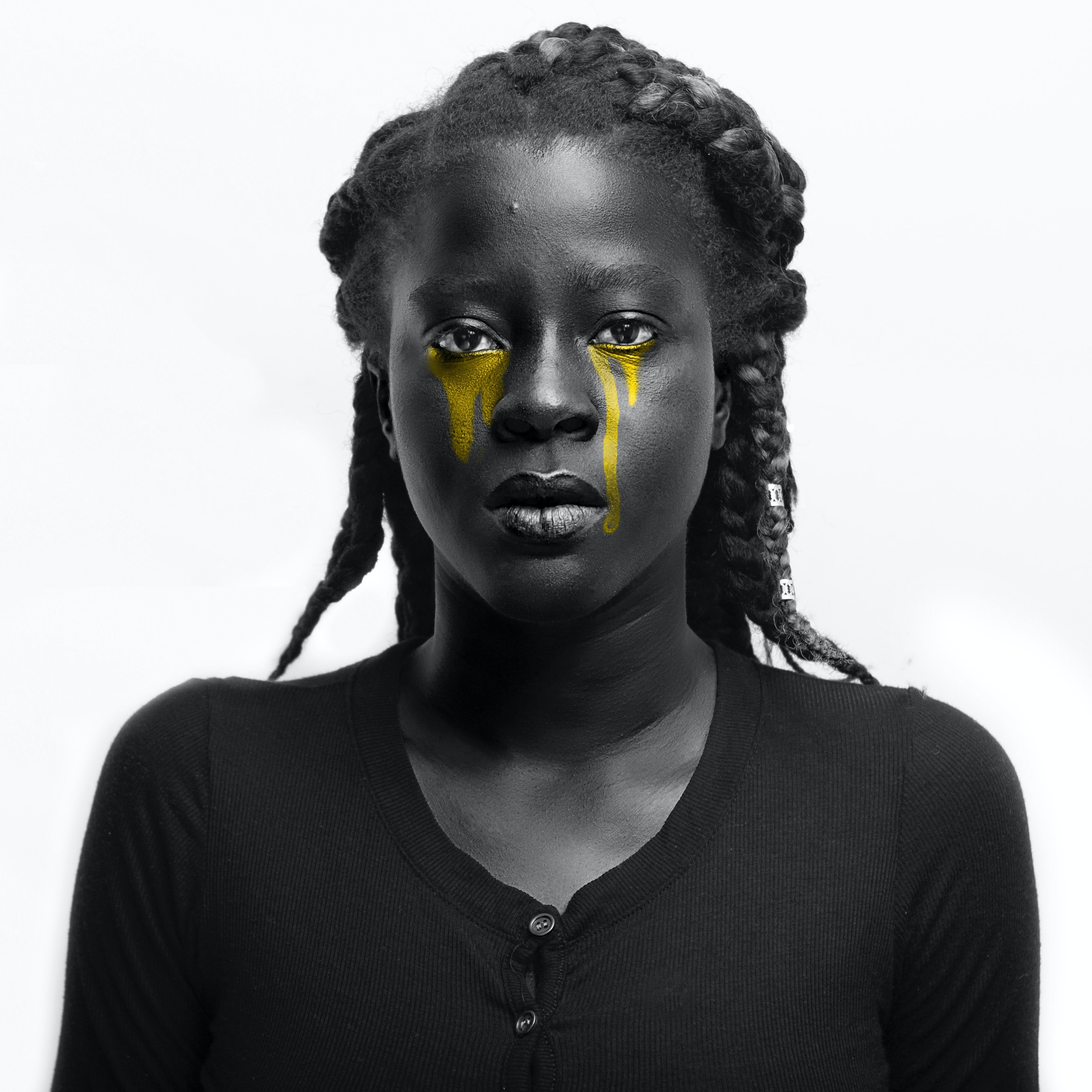 A monochrome phot of a woman with coloured eye make up as tears in yellow