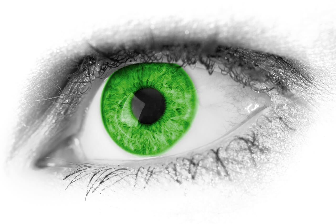 A close up of a greyscale eye with a green pupil.